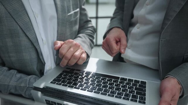 Two professionals collaborate on a laptop
