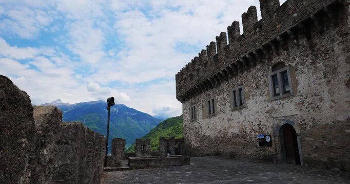 Bellinzona, Switzerland, May 18, 2026. Panning shot inside the inner courtyard of the historic medieval Castello di Montebello fortress, showcasing stone walls and alpine mountain peaks
