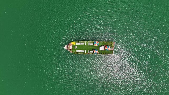 Aerial view of a tourist boat with colorful umbrellas on the green waters of Tanguar Haor in Sunamganj District, Sylhet Division, Bangladesh.