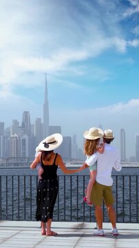 A tourist family standing at the Creek looks at the urban skyline of Dubai, UAE, during their city vacations