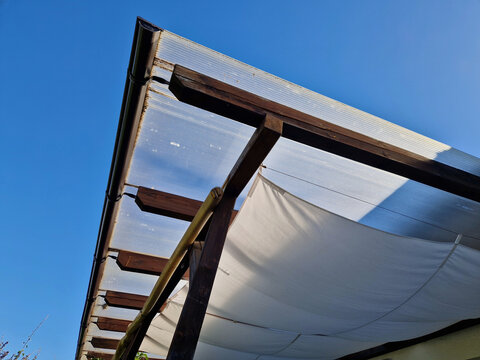 roof structure of wooden pergola, which combines solid top covering and additional textile shading. cellular polycarbonate, protects terrace Internal shading sliding canopy shade sail is installed dir