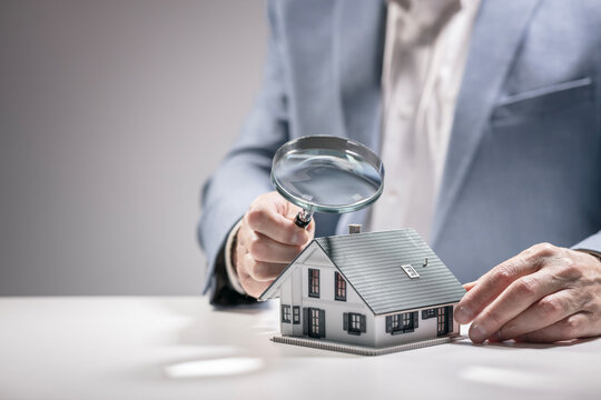 House model with man holding magnifying glass home inspection or searching for a house