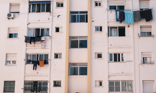 Fachada de edificio residencial con ropa tendida en ventanas y apartamentos urbanos en Espa&ntilde;a