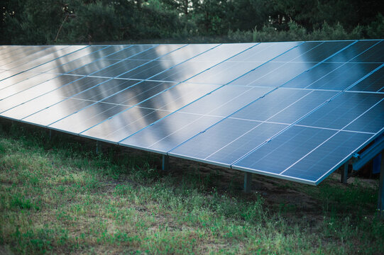 A small solar panel farm for generating eco-electricity on the edge of a forest in a recreation area at the base. Renewable energy, eco-friendliness, and environmental safety.