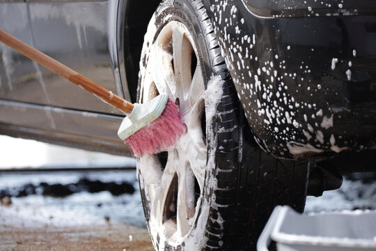 Cleaning car wheel with soapy brush and bubbles