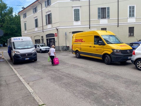 Yellow DHL delivery van parked on a street next to a white GLS van