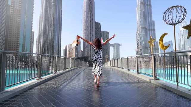 A happy tourist woman in a white dress on a sightseeing trip through Downtown Dubai, UAE, during her city vacations