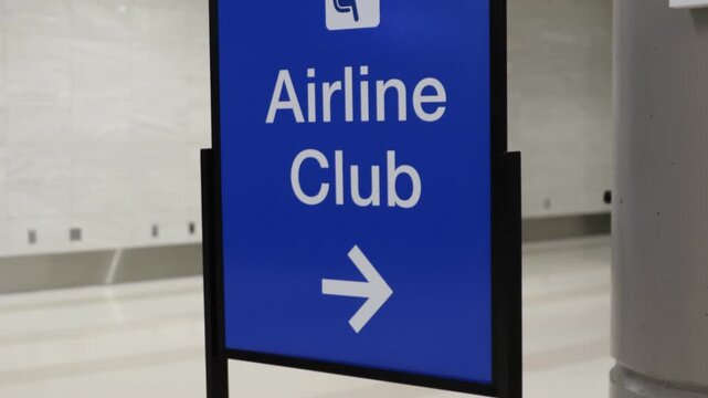 A blue directional sign at an airport with an arrow to the Airline Club