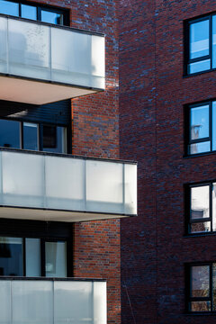 Stacked white balcony forms cut across a brick apartment building in Oslo, Norway, where modern residential architecture repeats window rhythm