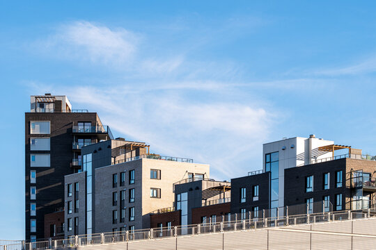 Open blue sky over Oslo, Norway, frames a modern apartment building skyline where residential architecture rises beyond a street barrier