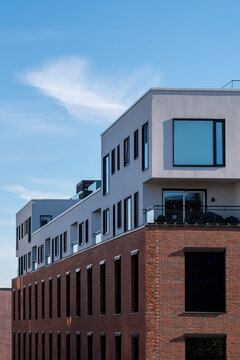 White roofline above brick walls in Oslo, Norway, marks a modern apartment building where residential architecture meets blue sky and clean geometry