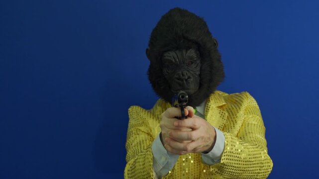 Man wearing a gorilla mask and a gold sequin jacket pointing a gun like a secret agent or gangster