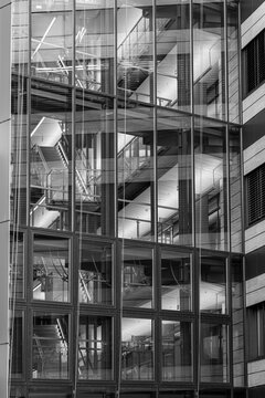 Glass atrium inside a modern office building reveals abstract architecture with staircase layers, window grids, and monochrome corporate depth