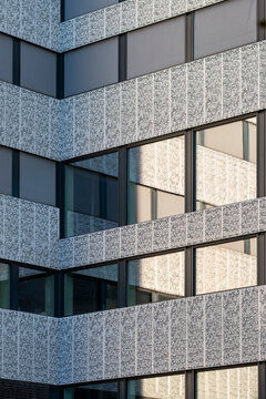 Texture bands define a modern office building where abstract architecture stacks window reflections across a bright urban facade corner