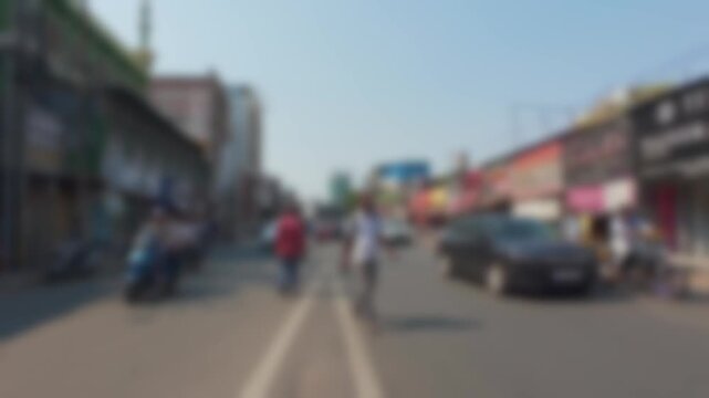 Busy commercial intersection with traffic and retail stores in Hyderabad. Blurry view of everyday urban transportation and shopping district lifestyle in Indian city during sunny afternoon.