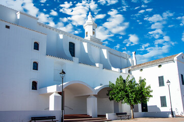 Iglesia Parroquial de San Luis Menorca, un día soleado con cielo azul y nubes blancas. © Menorcaevo
