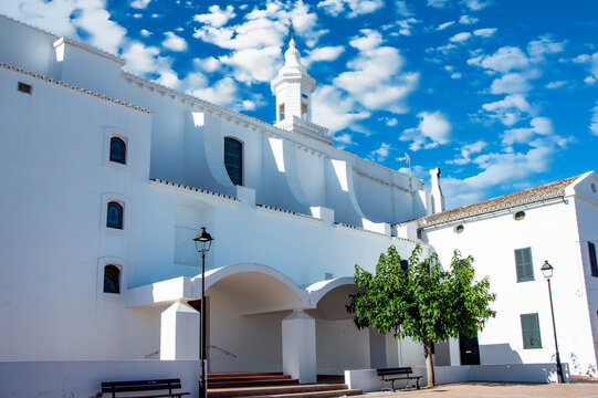 Iglesia Parroquial de San Luis Menorca, un d&iacute;a soleado con cielo azul y nubes blancas.