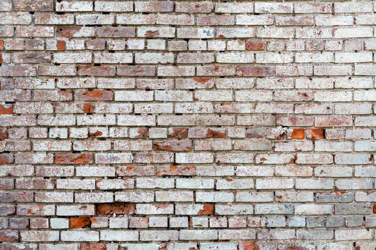 Damaged brick wall background with faded white paint