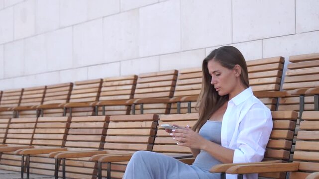 Woman Phone Bench: Young woman sitting on a bench looking at her phone.