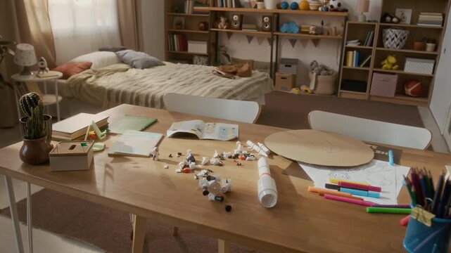 Messy study desk in kids bedroom showing scattered school supplies, books, and toys during slow zoom in. Clip is perfect for back to school promotions and parenting education videos