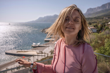 Fototapeta premium Woman sea balcony enjoying the ocean breeze on a sunny hotel terrace