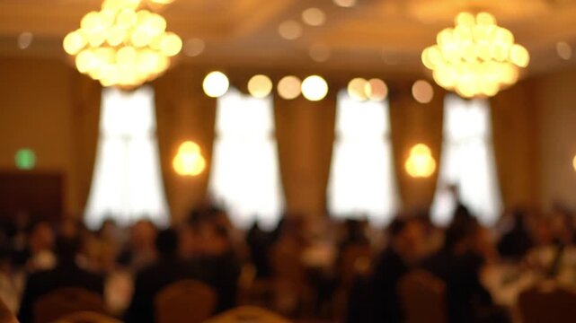 Out of Focus Blurred Background of a Formal Banquet Hall Event with Chandeliers and People Seated at Round Tables