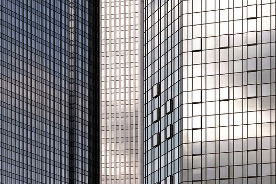 Reflective glass towers in Frankfurt, Germany create modern financial architecture with curved facade grids and dense urban highrise rhythm