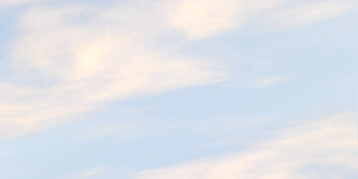 Pastel light blue sky background with soft light yellow wispy clouds. Calm ethereal sunrise or sunset atmosphere backdrop for beautiful minimalistic and peaceful graphic designs