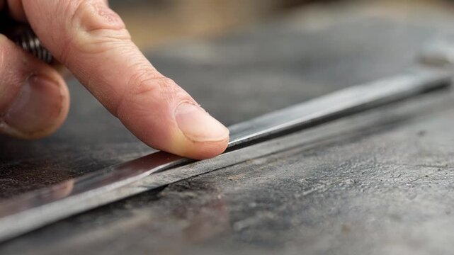 Closeup of hand using a trowel to carefully press and shape a thin margin blade highlighting precision in masonry tool crafting