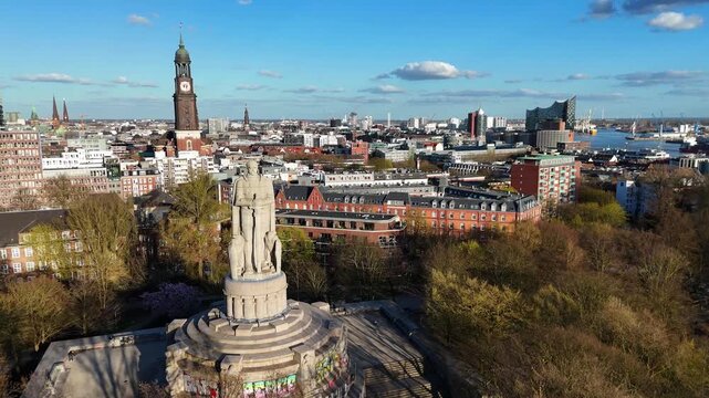 Aerial view of the Bismarck Monument surrounded by green trees with St. Michael's Church and the Elbphilharmonie in the background, Hamburg, Hamburg, Germany.