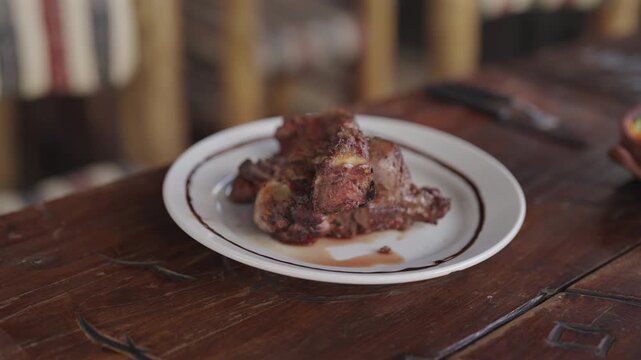 A close-up of a traditional Argentine chivo dish served on a rustic wooden table. Ideal for culinary blogs or cultural documentaries exploring Argentine cuisine.