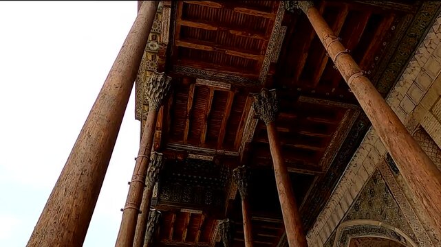 Low angle view of carved wooden pillars and ornate ceiling of Bolo Hauz Mosque
