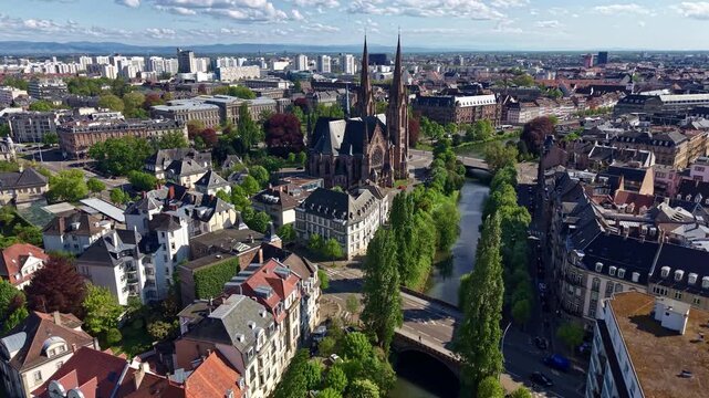 Historic neo-gothic Eglise Saint-Paul situated at intersection of Ill river and Aar river in Strasbourg, France. Aerial forward, cityscape