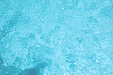 Obraz na płótnie Canvas Top view of crystal clear blue swimming pool water texture with gentle ripples and sunlight reflections for summer background.