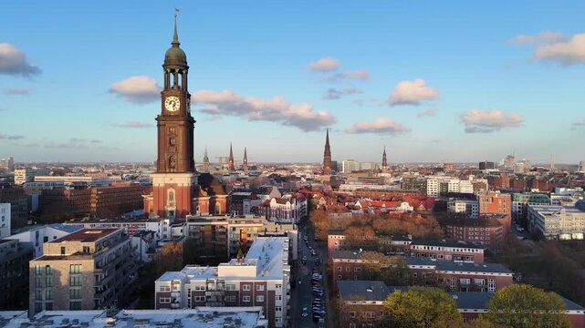 Aerial view of St. Michaeliskirche with its iconic clock tower overlooking the historic rooftops and urban skyline under a blue sky in Hamburg, Hamburg, Germany.