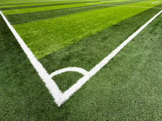 Obraz premium Corner of a soccer field with white boundary lines on green grass turf in an empty outdoor stadium