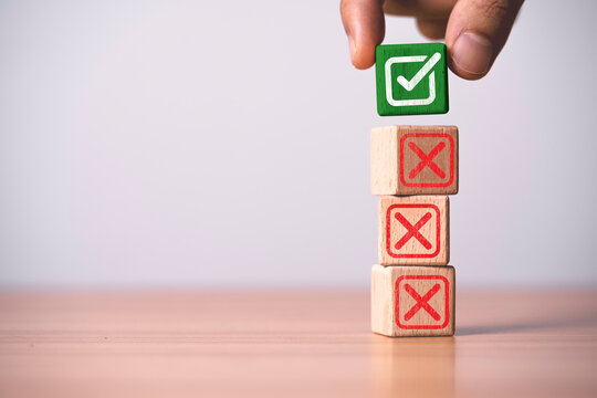 Hand placing checkmark block above incorrect symbols, representing quality control, approval process, decision making, business evaluation, validation, compliance, and successful selection.