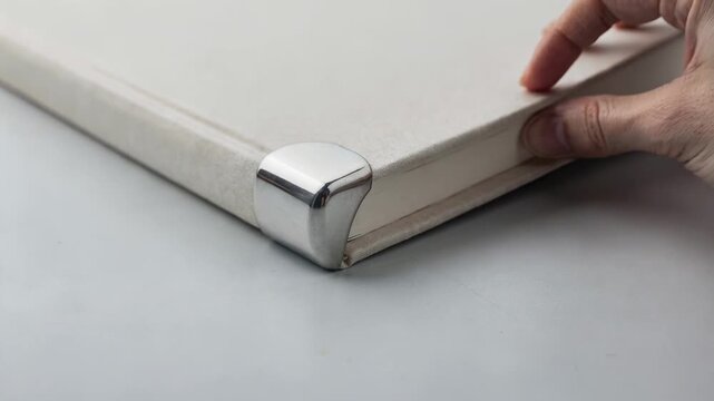 Medium shot focusing on rounded metal protectors being installed on a blankbook corner showcasing smooth finishes and added safety for frequent use