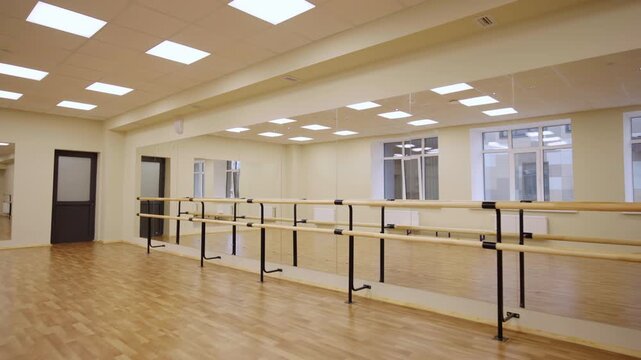 Large mirror and wood barres in illuminated dance class interior. Empty gym for ballet lessons conduction in art center. Gymnastics