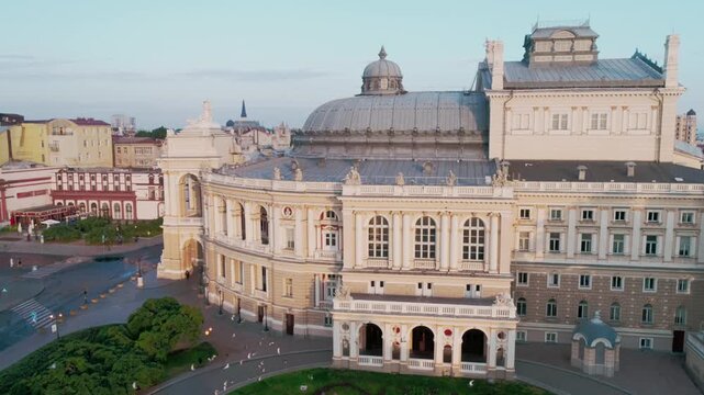 Aerial drone shot of the iconic Odessa National Opera and Ballet Theater at golden sunrise. Historic neoclassical architecture, empty square, city skyline. Ideal for travel and culture content.