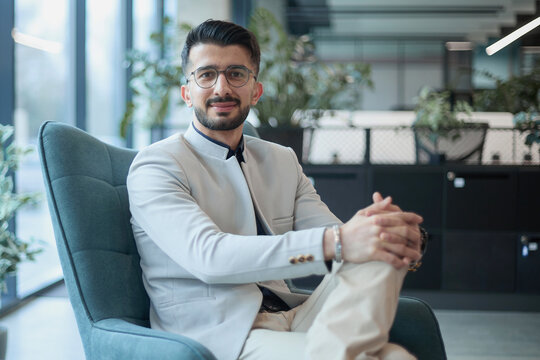 A man in a suit is sitting in a chair in front of a laptop