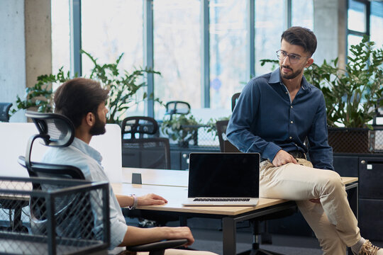 Two men are sitting at a desk talking