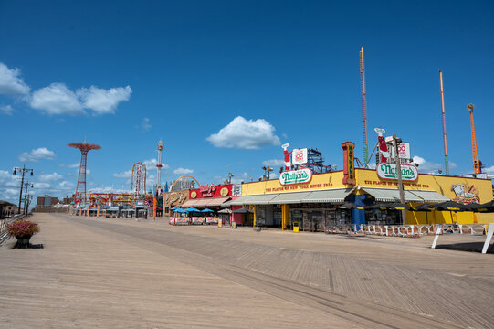 New york, usa august 21,2024. The iconic coney island boardwalk under a clear blue sky, featuring nathan's famous and amusement rides