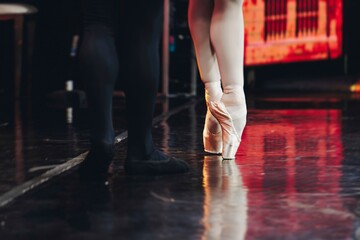 Ballet dancers couple during performance repetition, classic ballet rehearsal practicing in ballroom, view of legs in pointe shoes, ballerina and ballet dancer on a concert hall theatre stage floor © tsuguliev