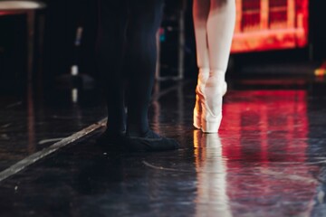 Ballet dancers couple during performance repetition, classic ballet rehearsal practicing in ballroom, view of legs in pointe shoes, ballerina and ballet dancer on a concert hall theatre stage floor © tsuguliev