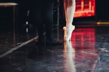 Ballet dancers couple during performance repetition, classic ballet rehearsal practicing in ballroom, view of legs in pointe shoes, ballerina and ballet dancer on a concert hall theatre stage floor © tsuguliev