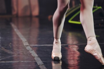 Ballet dancers couple during performance repetition, classic ballet rehearsal practicing in ballroom, view of legs in pointe shoes, ballerina and ballet dancer on a concert hall theatre stage floor © tsuguliev