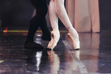 Ballet dancers couple during performance repetition, classic ballet rehearsal practicing in ballroom, view of legs in pointe shoes, ballerina and ballet dancer on a concert hall theatre stage floor © tsuguliev