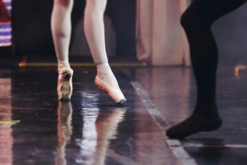 Ballet dancers couple during performance repetition, classic ballet rehearsal practicing in ballroom, view of legs in pointe shoes, ballerina and ballet dancer on a concert hall theatre stage floor © tsuguliev