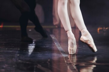 Ballet dancers couple during performance repetition, classic ballet rehearsal practicing in ballroom, view of legs in pointe shoes, ballerina and ballet dancer on a concert hall theatre stage floor © tsuguliev